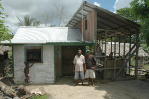 Stanly Auger (left) in front of his home